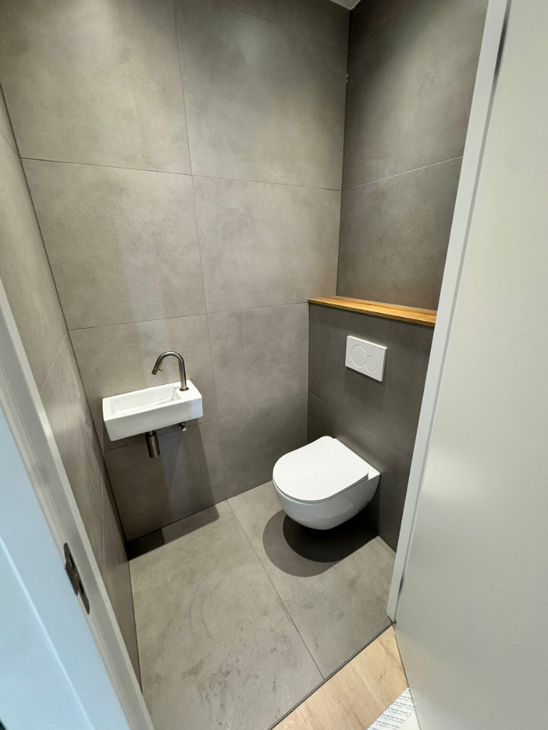 Modern toilet met betonlook tegels en houten plank