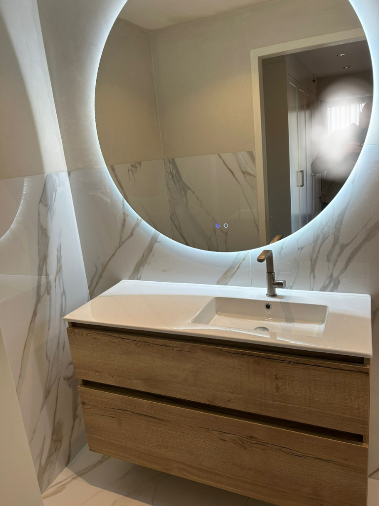 Wastafel met marmerlook wand en spiegel met verlichting