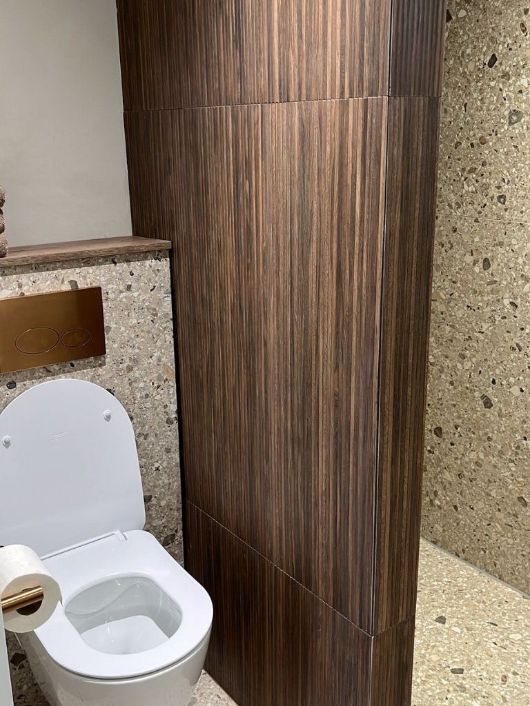Materialen dichtbij: terrazzo, hout en een gouden bedieningsplaat